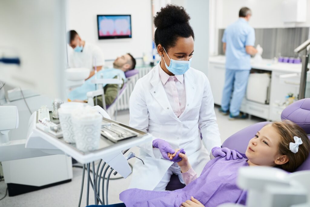 Child at her first dental visit holding the dentist’s hand at Hillcrest Family Dentistry in Medford, OR